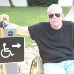 Bob wearing a black t-shirt and sunglasses looking cool next to a wheelchair sign
