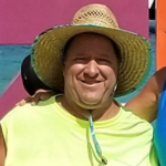 A male wearing a light brown hat and a neon t-shirt.