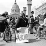 black and white photo of many people in wheelchairs protesting at the capitol. Photo from Crip Camp film